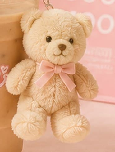 A small tan teddy bear keychain clipped to a cup of iced coffee